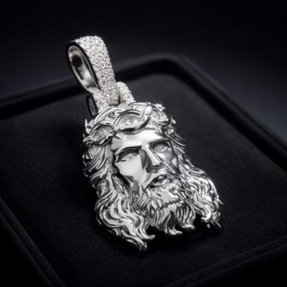 Silver pendant with a detailed face design on a black background