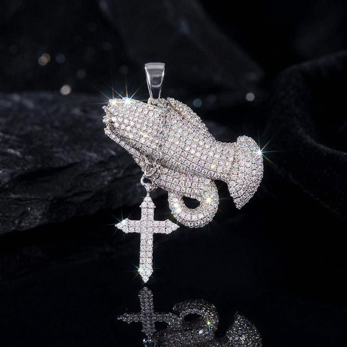 Silver pendant with praying hands and cross on a black background