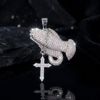 Silver pendant with praying hands and cross on a black background