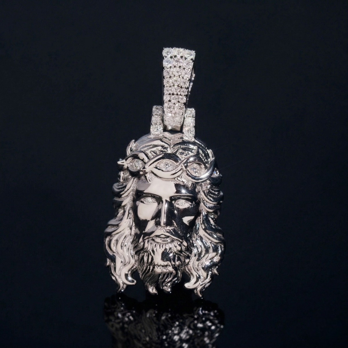 Silver pendant with a face design on a black background