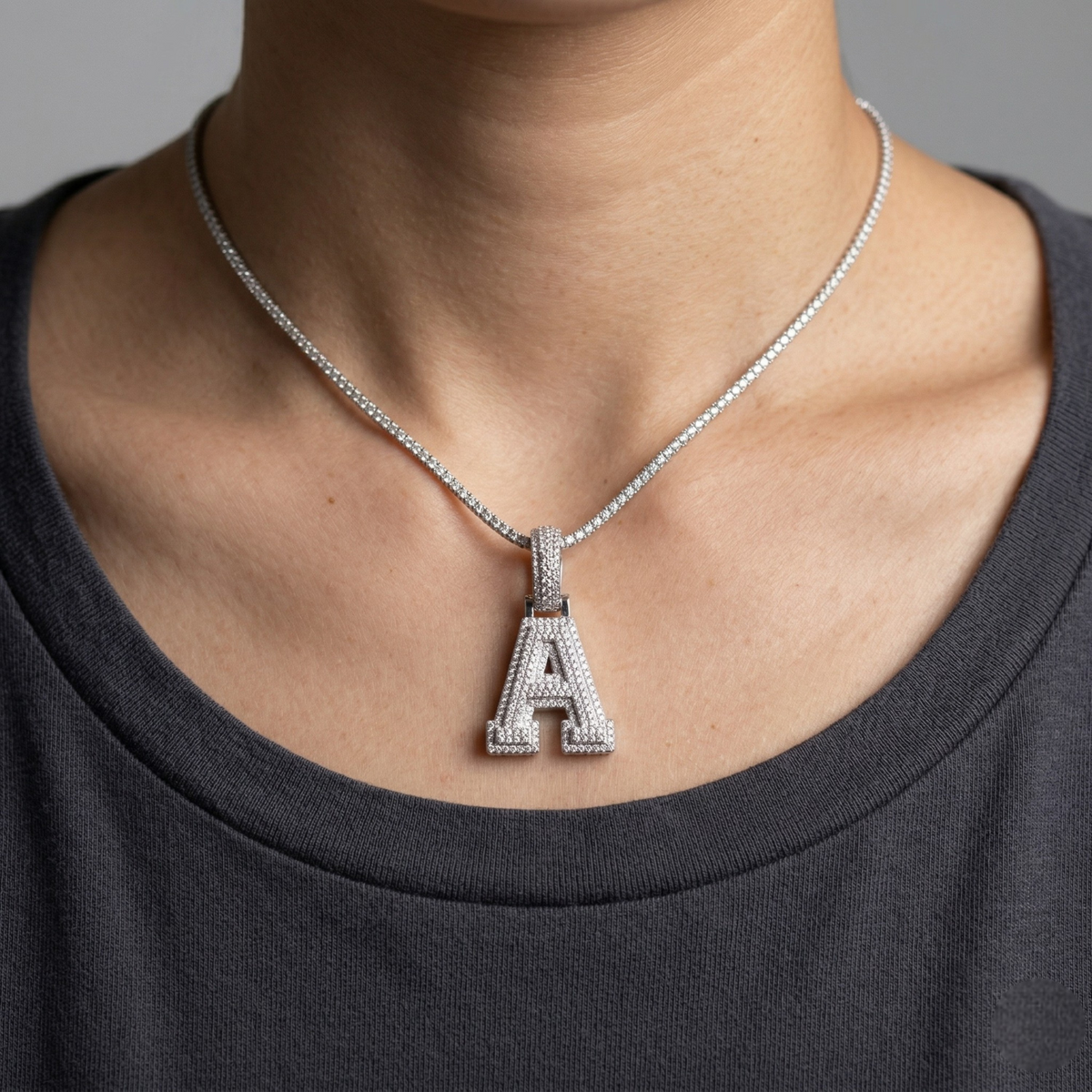 Necklace with a silver 'A' pendant worn by a person against a neutral background