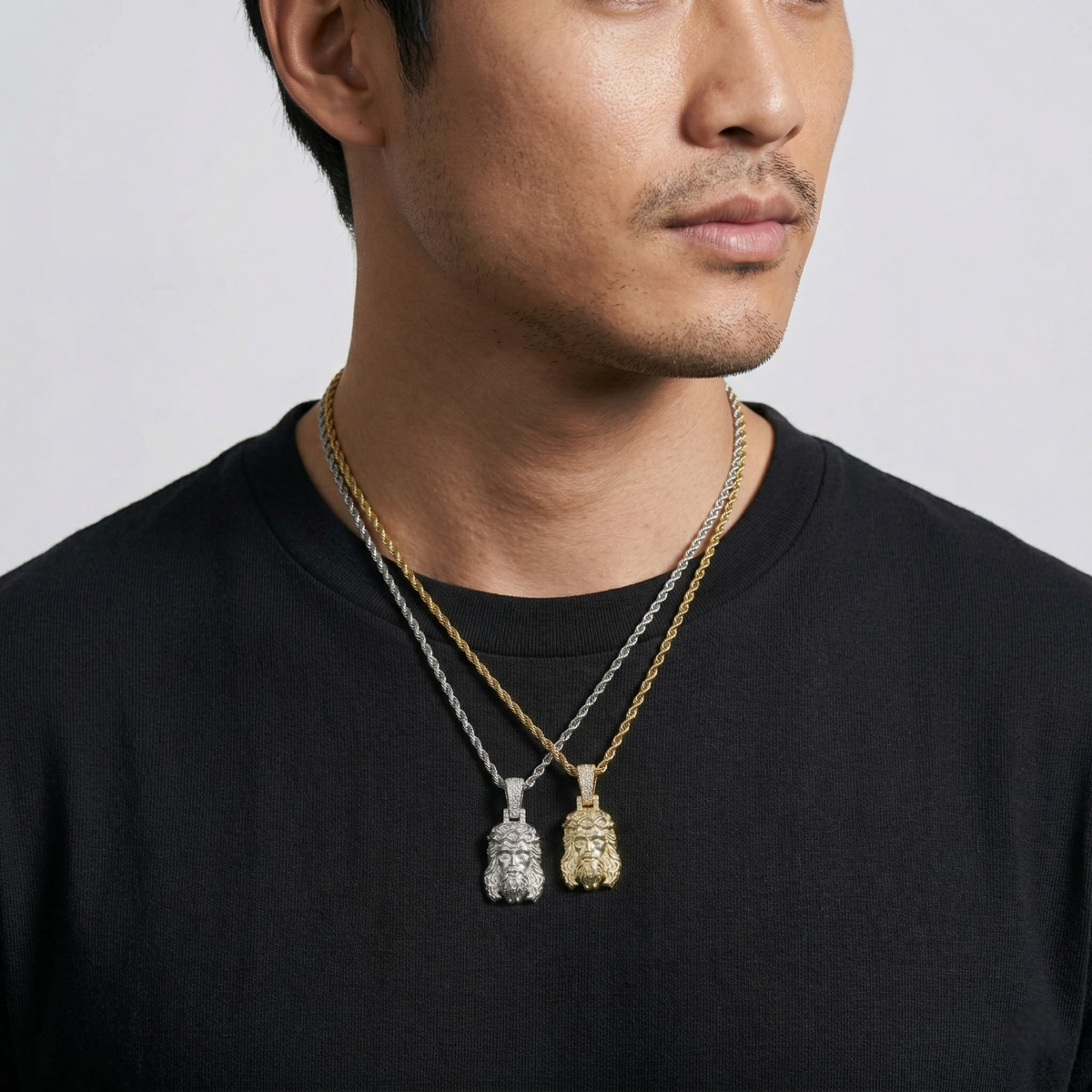 Man wearing two necklaces with pendants on a plain background