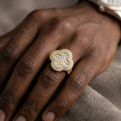 Close-up of a hand wearing a gold and diamond ring on a neutral background