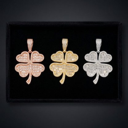 Three clover-shaped pendants in rose gold, yellow gold, and white gold on a black background.