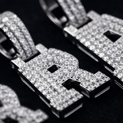 Close-up of a diamond-encrusted pendant with letters on a dark background